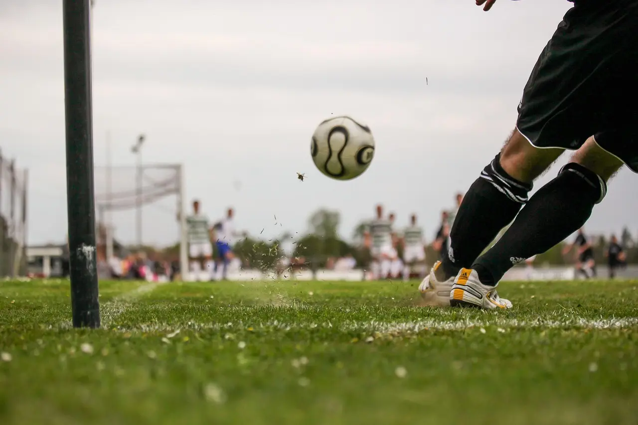 En spelare slår till bollen på fotbollsplanen