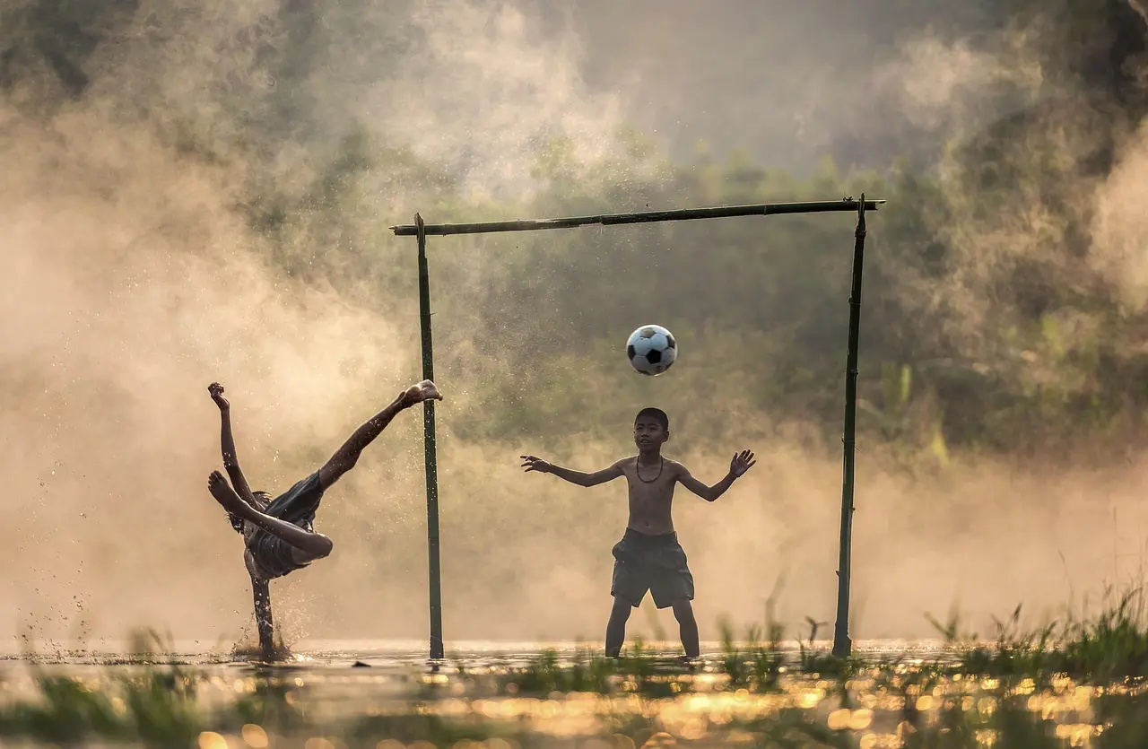 Barn spelar fotboll vid ett hemmagjort mål i vattnet