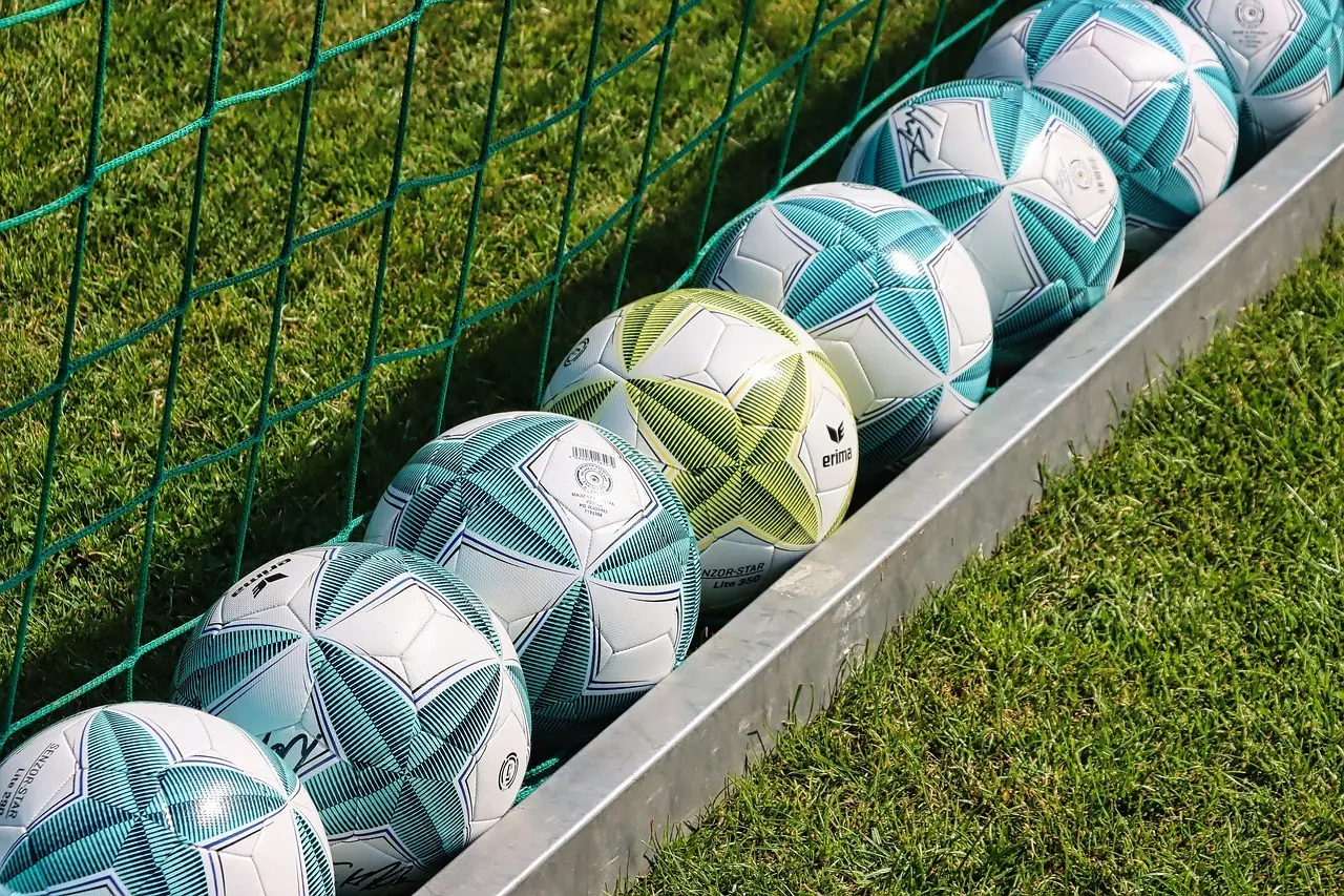En rad fotbollar på gräset vid ett mål